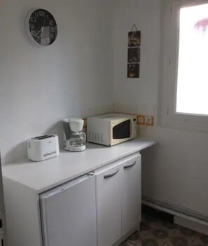 Eine kleine Küchenzeile mit Mikrowelle, Toaster und Kaffeemaschine auf einer weißen Arbeitsplatte.