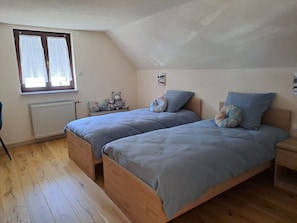 A bedroom with two beds, a window, a radiator, and a teddy bear. - Vacation Home "Maurer" with Private Terrace, Shared Garden & Wi-Fi (Aschbach)