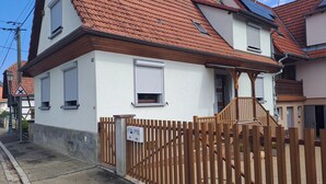 Et toetagers hus med røde tegltage, hvide vægge og et træhegn.