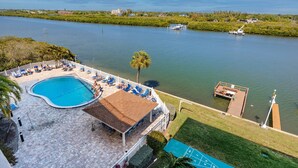 A pool area with lounge chairs and a small boat dock. - Updated Corner Unit! Views of the Gulf and Intercoastal! FREE Activities Included! ~ 401 Bayshores (Indian Shores)