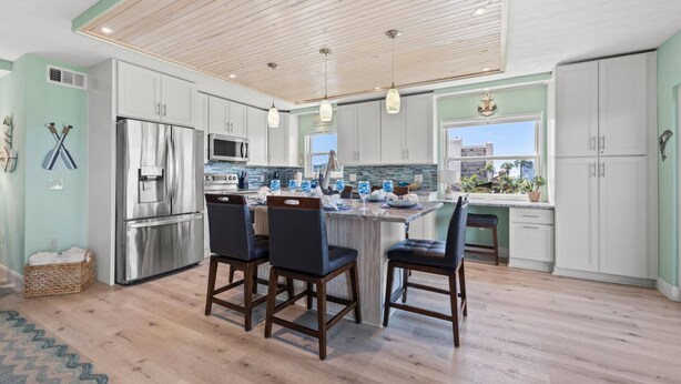 A modern kitchen with a central island, stainless steel appliances, and a view to the outside. - Updated Corner Unit! Views of the Gulf and Intercoastal! FREE Activities Included! ~ 401 Bayshores (Indian Shores)