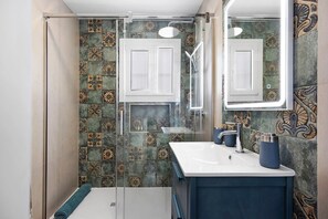 A bathroom with a shower, a sink, and a mirror.