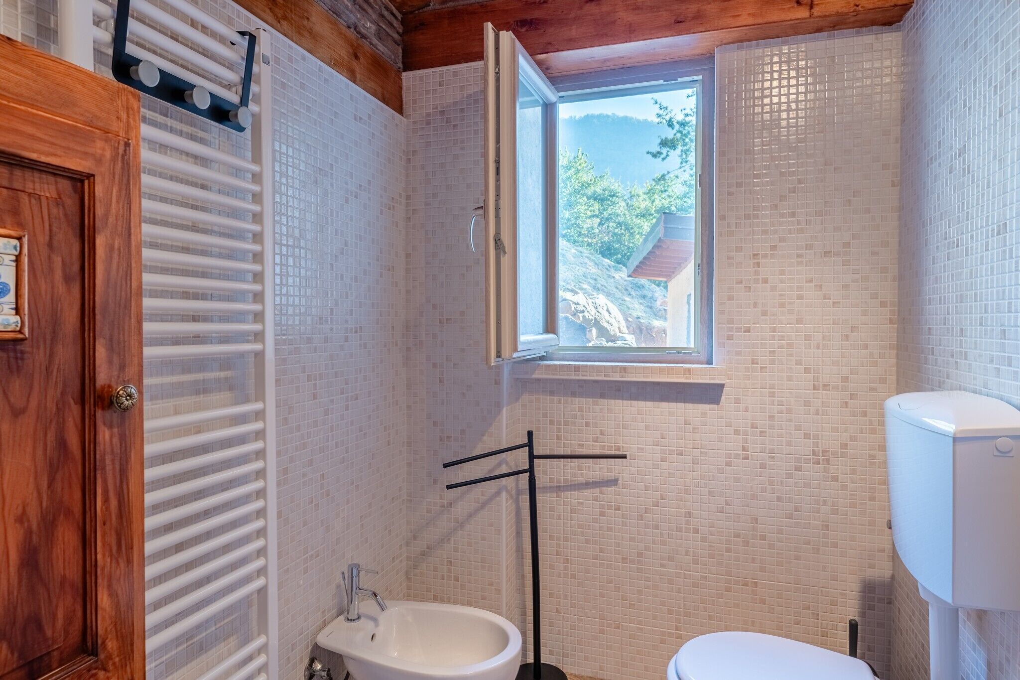 A bathroom with a window, a toilet, a bidet, and a sink.