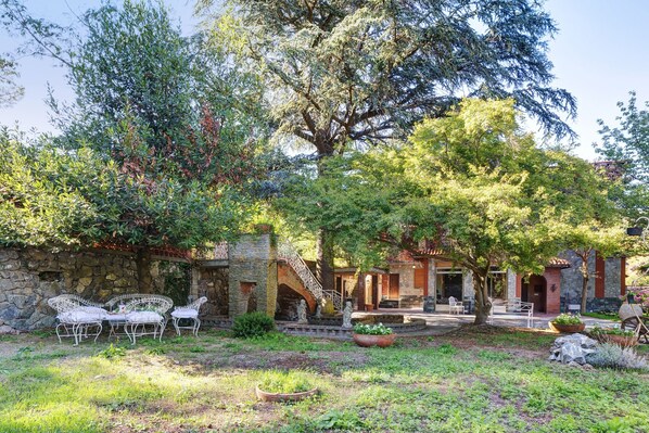 A stone building with a patio, outdoor seating, and a staircase leading to the entrance.