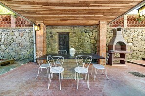 Un patio al aire libre con un muro de piedra, una chimenea de ladrillo y una mesa con sillas.