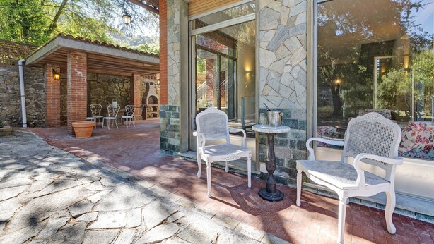 Un bâtiment en pierre doté d’un patio comprenant deux chaises en osier blanc et une petite table.