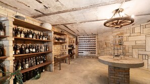 Une cave à vin avec des étagères en bois, une table centrale et un comptoir en pierre.