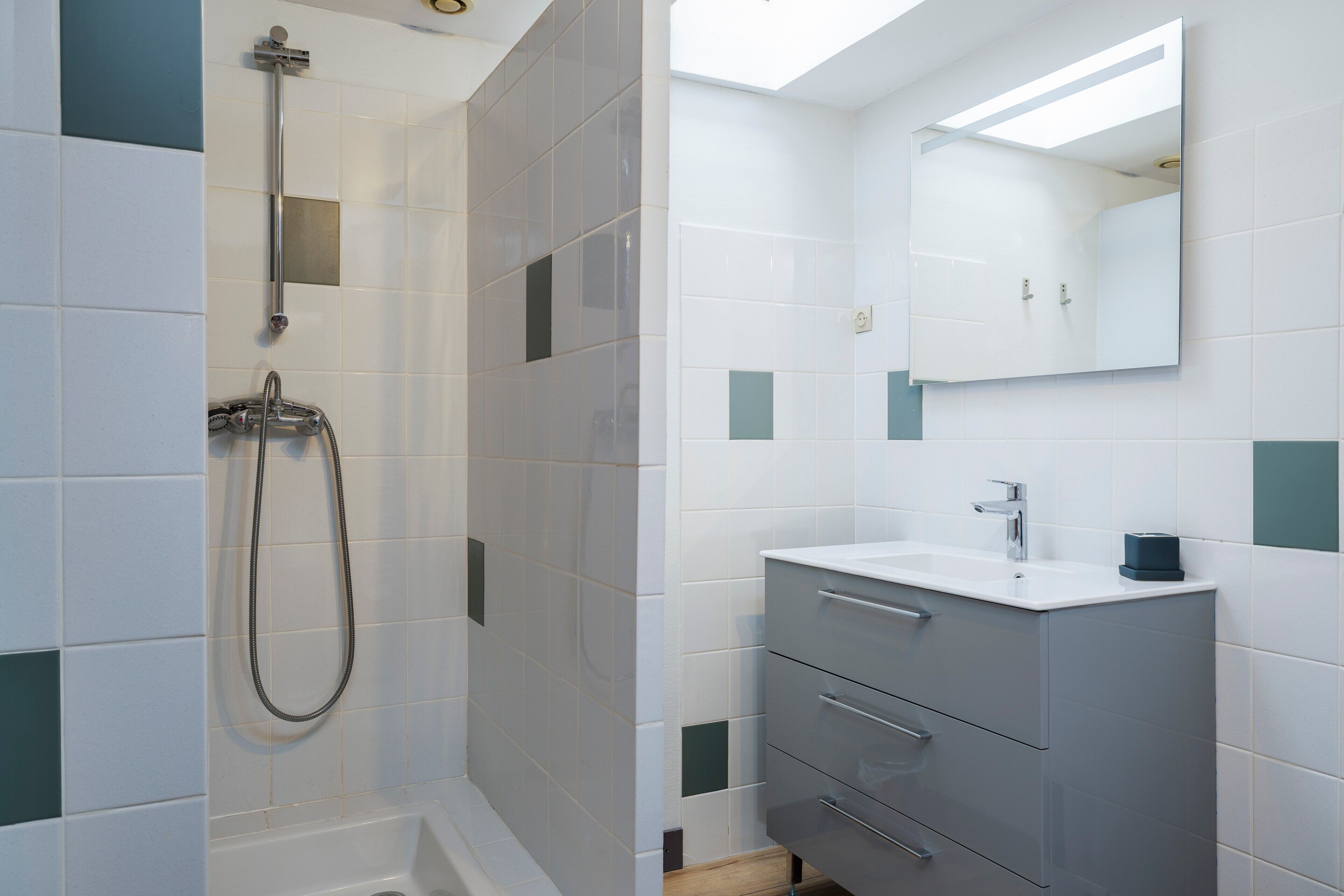 A bathroom with a shower, a sink, a mirror, and a cabinet.