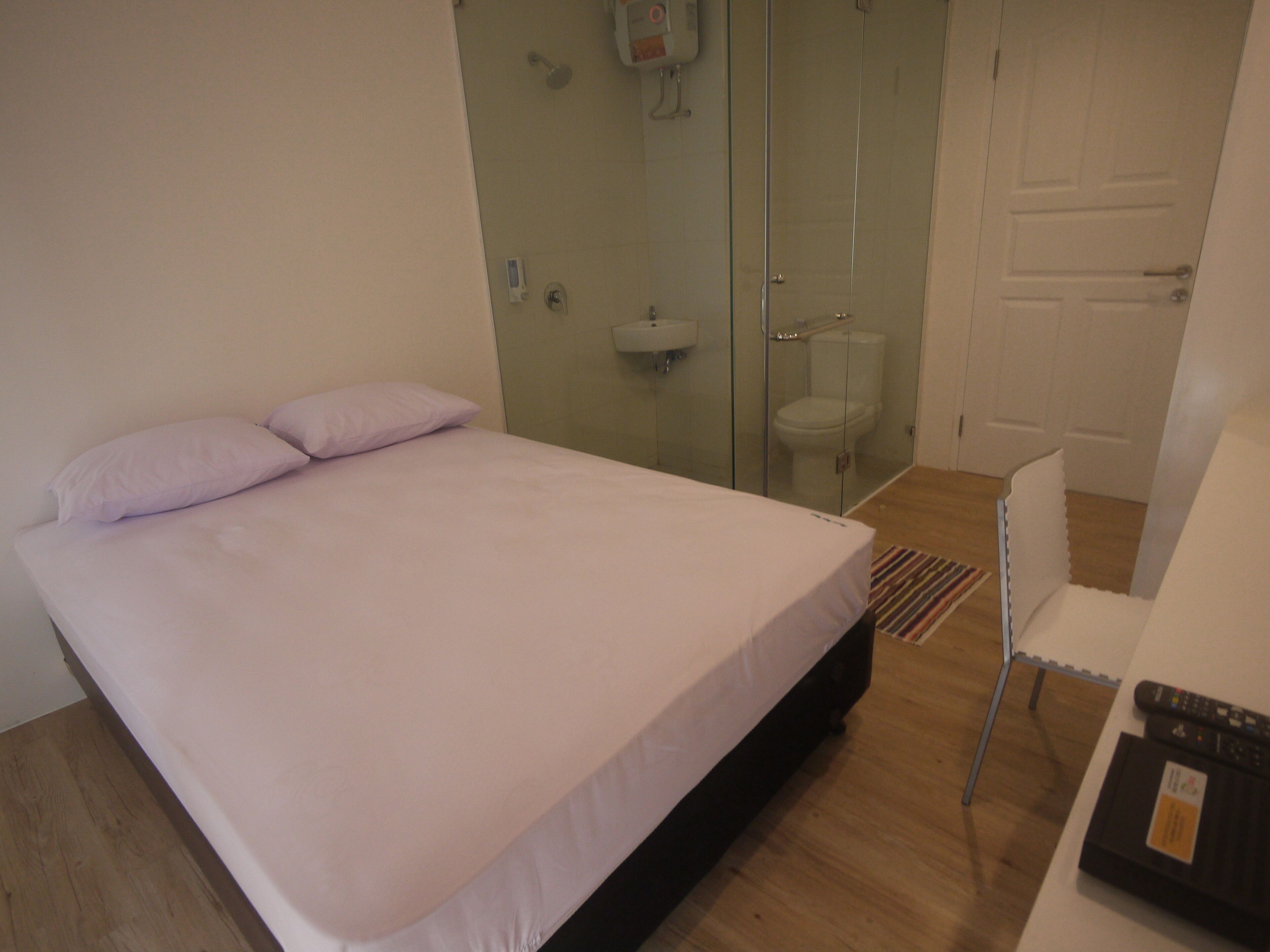Un dormitorio con cama, ducha y retrete.