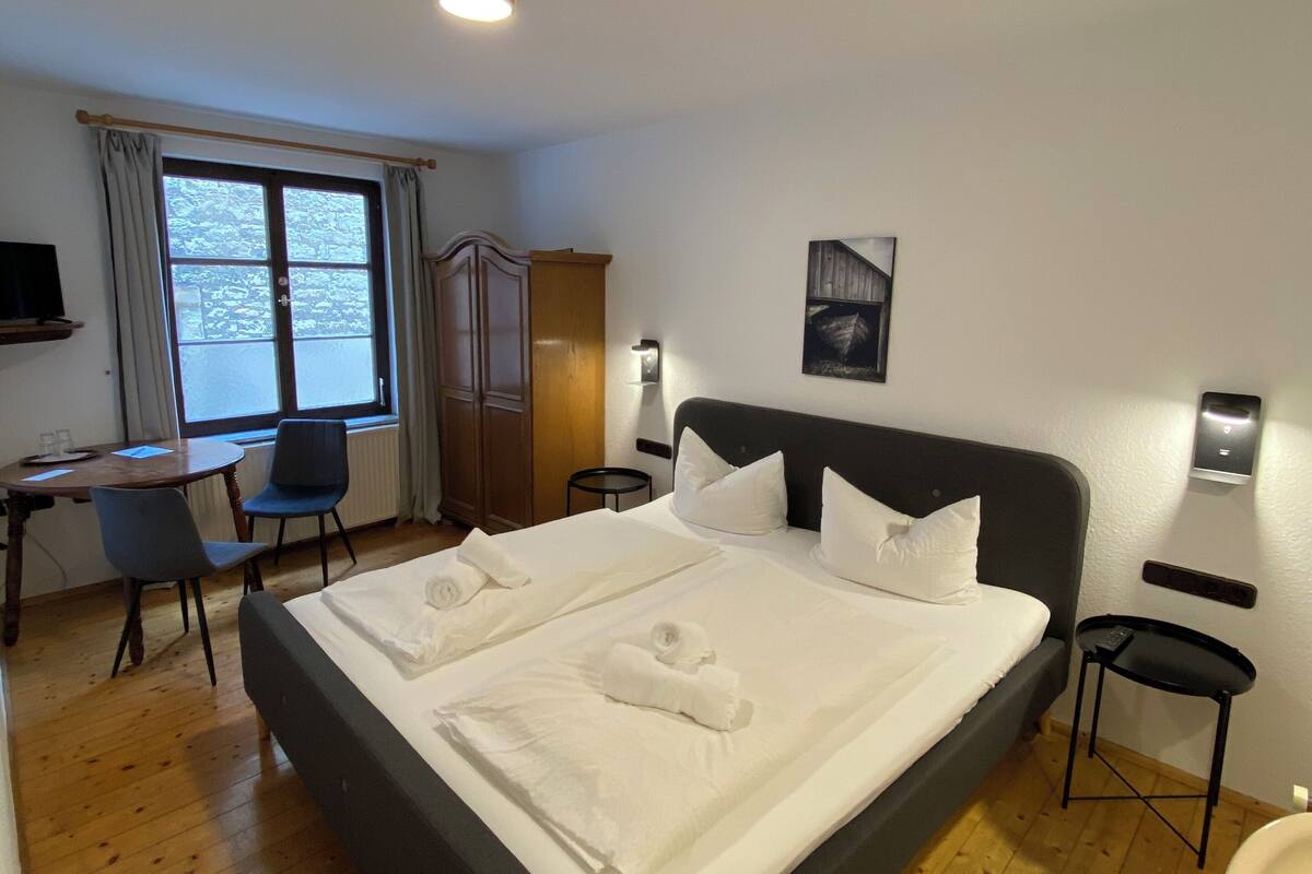 Une chambre d’hôtel avec un grand lit, un bureau, une chaise, une armoire et une salle de bain.