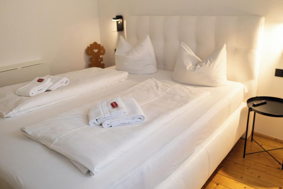Une chambre d’hôtel avec deux lits, chacun agrémenté de serviettes blanches et d’oreillers soigneusement pliés.