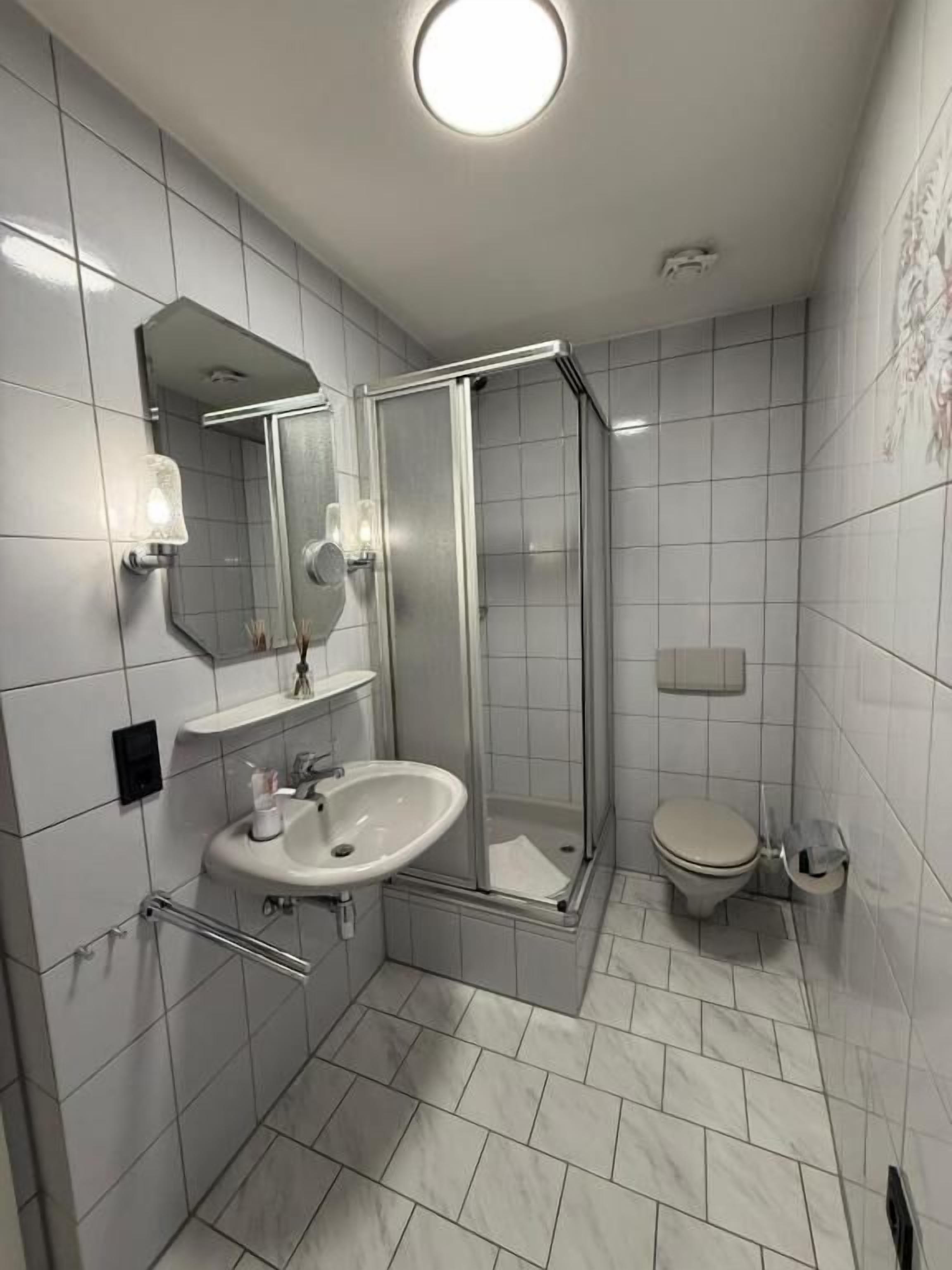 A modern bathroom with a glass-enclosed shower, a white sink, and a toilet.