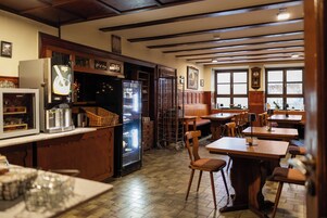 Un restaurante con mesas y sillas de madera, un refrigerador y una barra con diversos productos.