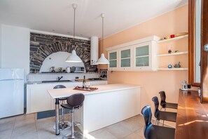 Una cocina moderna con una isla central, taburetes de bar e iluminación colgante.
