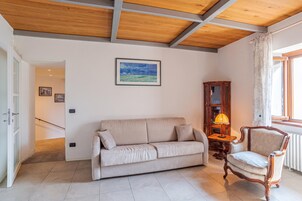 Una sala de estar con un sofá, un sillón, una lámpara y un cuadro en la pared.