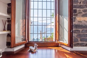 Una habitación con un ventanal grande, piso de madera y una mesa de centro con tazas y una cafetera.