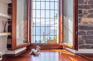 Una habitación con un ventanal grande, piso de madera y una mesa de centro con tazas y una cafetera.