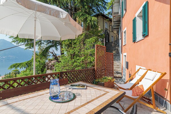 A terrace with a table, chairs, and an umbrella.