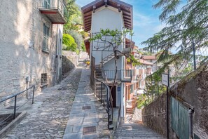 Una estrecha escalera de piedra que sube hacia un edificio con un balcón de madera.