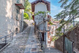 Una estrecha escalera de piedra que sube hacia un edificio con un balcón de madera.