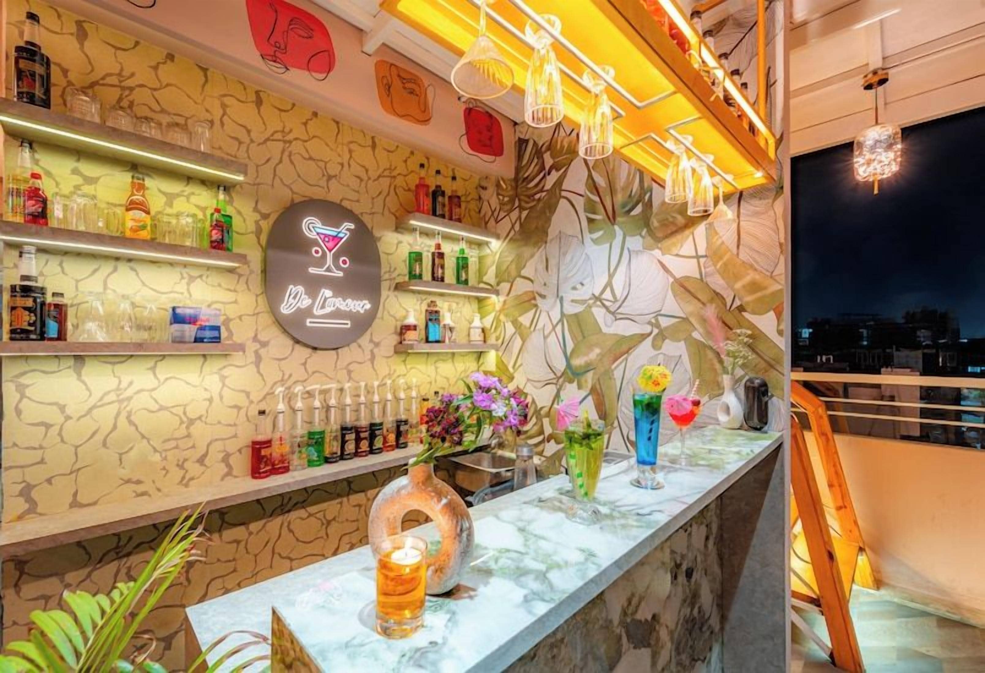 A bar area with shelves of bottles, a neon sign, and decorative plants.