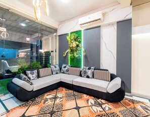 A modern living room with a sectional sofa, a patterned rug, and a green vertical garden wall.