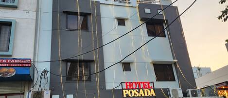 Un hotel llamado 'Hotel Posada' con un letrero, un restaurante 'De Limone Restaurant' encima, y plantas en macetas al frente.