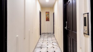 Un couloir doté d’un sol en marbre, d’une porte noire et d’un tableau accroché au mur.