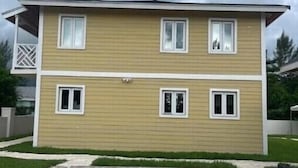 Un edificio residencial de dos plantas con techo plano, un porche delantero y una entrada para coches.