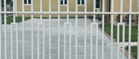 A residential house with a fenced driveway, a garage, and a well-maintained lawn.