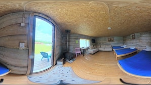 Habitación circular con paredes de madera, chimenea, sofá y dos camas.