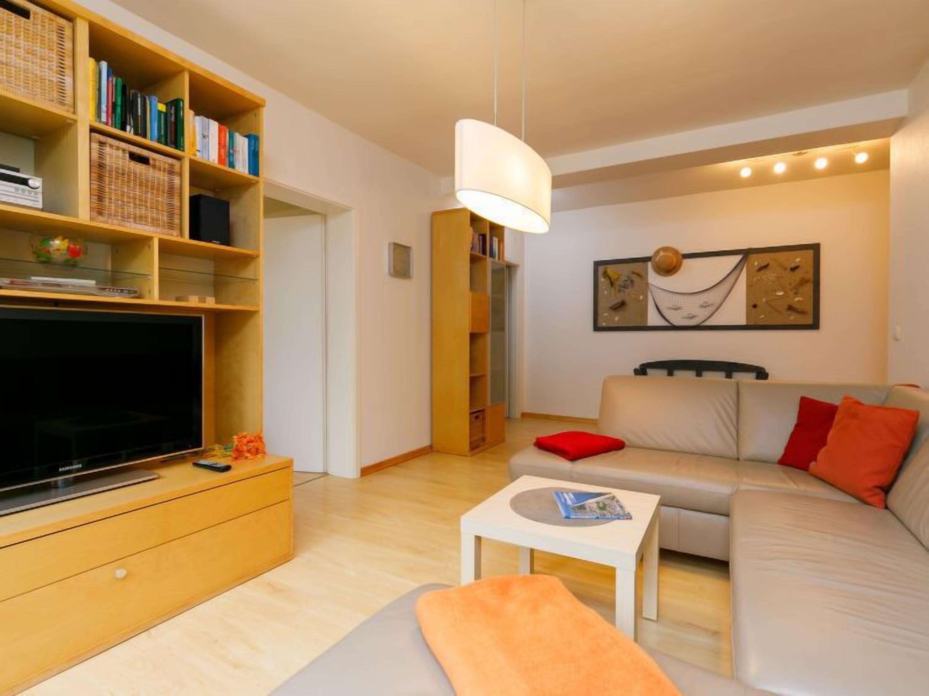 Un soggiorno moderno con un divano, un tavolino, una TV e una libreria.