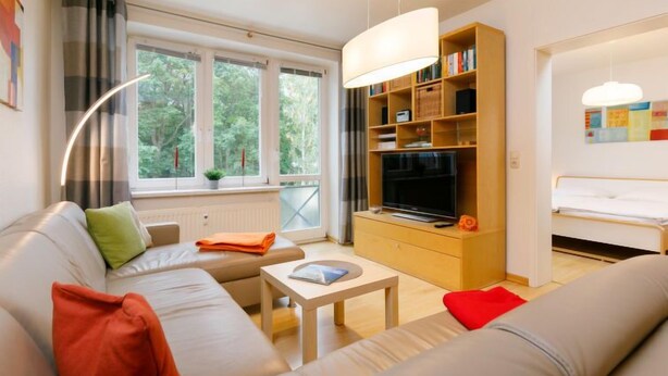 Ein modernes Wohnzimmer mit einer Couch, einem Couchtisch, einem Fernseher und einem Bücherregal.