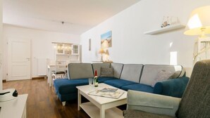 A modern living room with a sectional sofa, a coffee table, and a dining area in the background.
