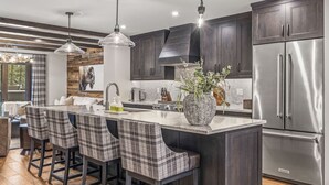 Una cucina moderna con mobili in legno scuro, elettrodomestici in acciaio inossidabile e un'isola centrale con sgabelli da bar.