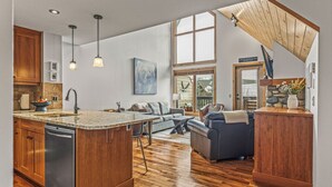 A spacious kitchen with a large island, wooden cabinets, and pendant lighting. - Wake Up to Three Sisters | Penthouse Condo (Canmore)