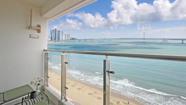 A balcony with a view of the beach and a bridge.