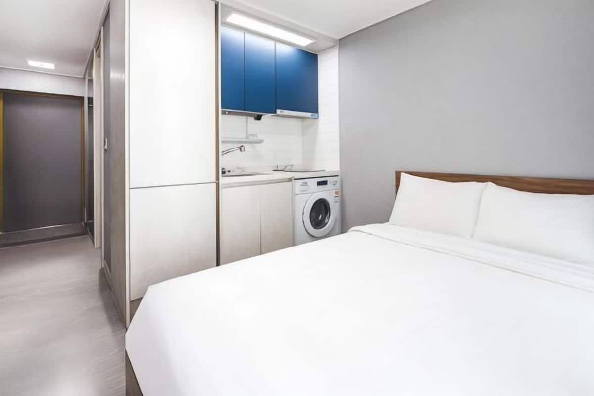 Une chambre d’hôtel équipée d’un lit, d’une machine à laver et d’une kitchenette.