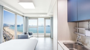A modern hotel room with a large window offering a view of a beach and cityscape.