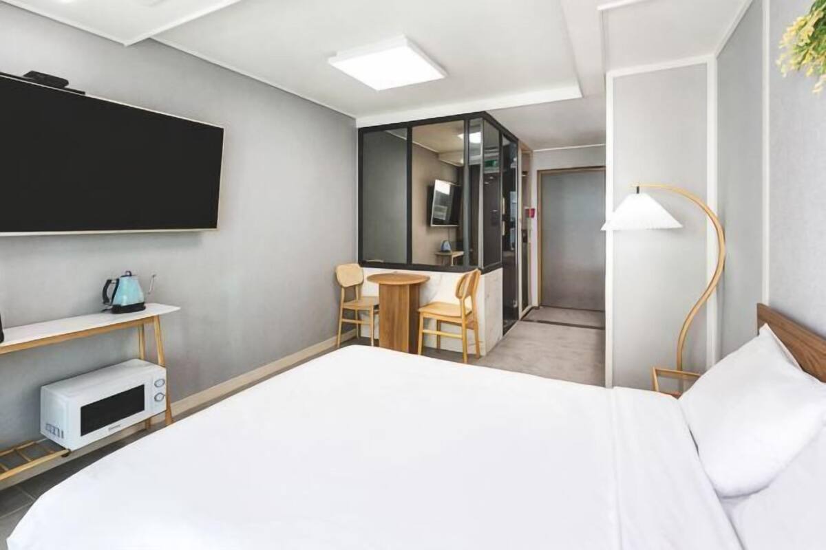 Une chambre d’hôtel équipée d’un lit, d’une télévision, d’un four à micro-ondes, d’un bureau avec des chaises et d’une lampe.