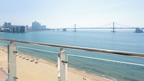 A beach view with a large bridge in the background.
