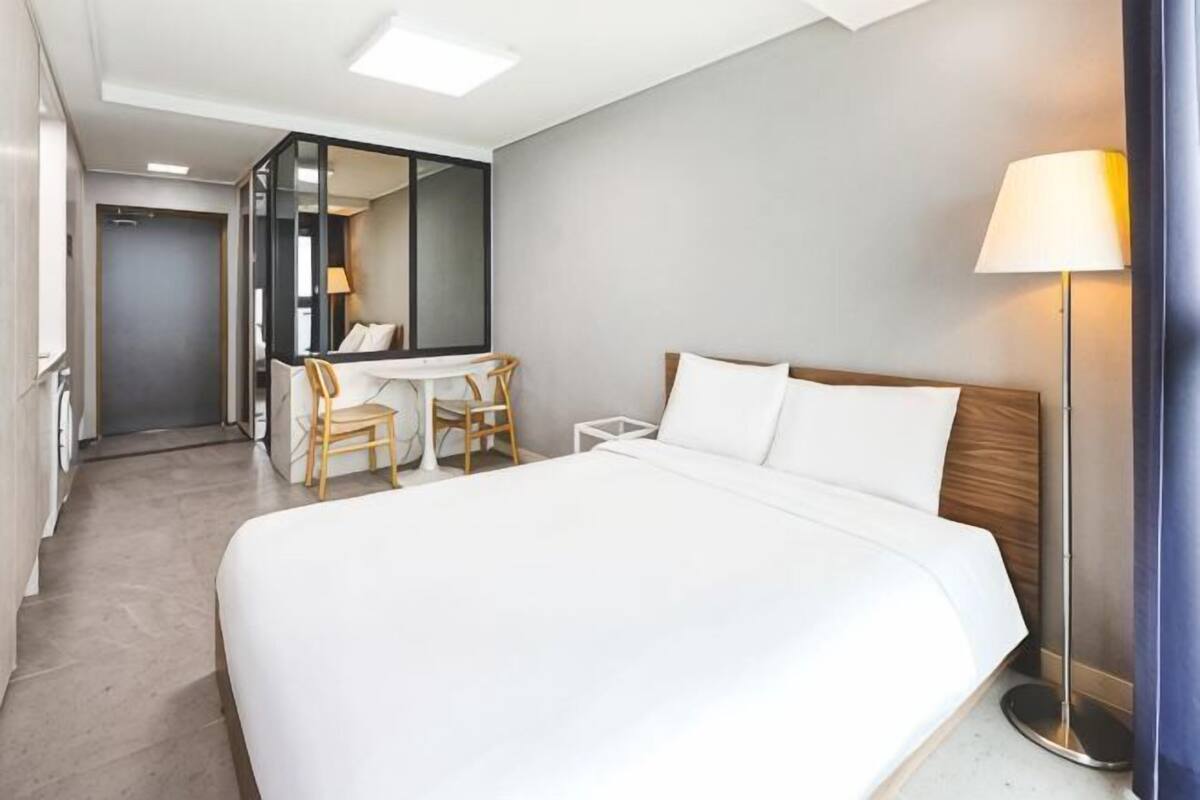 Une chambre d’hôtel avec un grand lit, un bureau, une chaise, un miroir et une lampe sur pied.