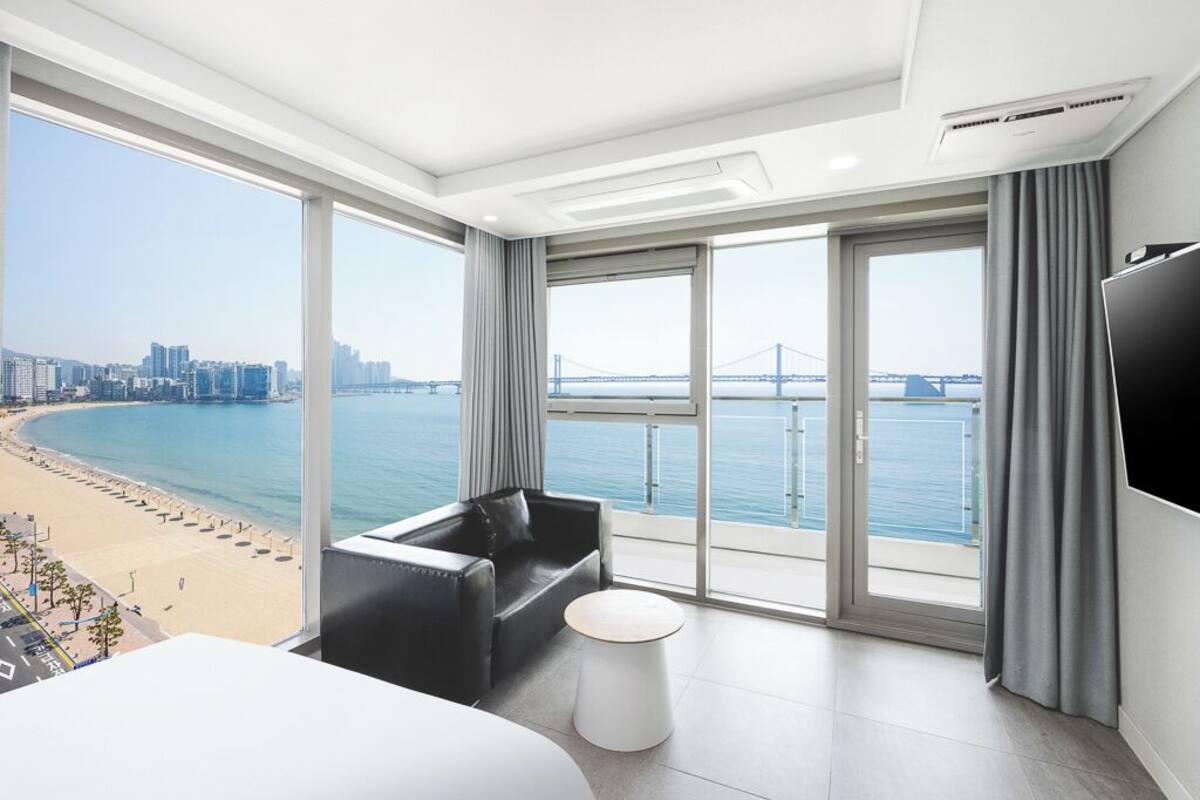 Une chambre d’hôtel moderne dotée d’un grand balcon, d’un lit, d’un canapé et d’une télévision.