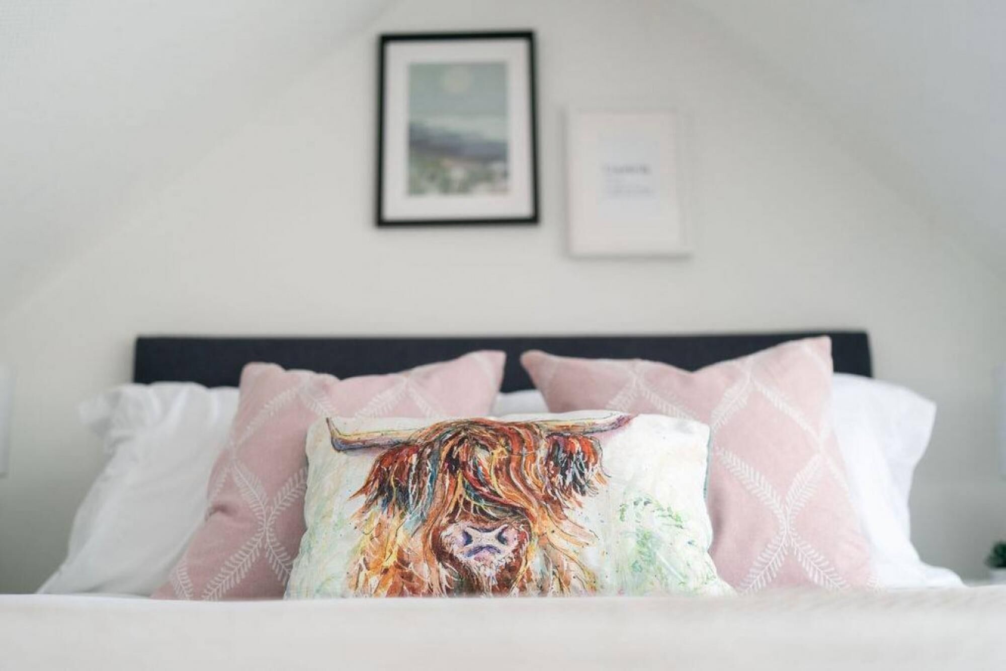 A bed with a colorful pillow, a framed picture on the wall, and a small sign.
