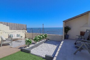 A rooftop patio with outdoor seating, a small garden area, and a view of the sea. - Coorie By The Coast Beachfront Cottage Arbroath (Arbroath)