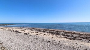 Una playa con cielos despejados y aguas tranquilas.