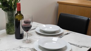 Een eettafel gedekt met witte borden, een wijnglas en een fles wijn.