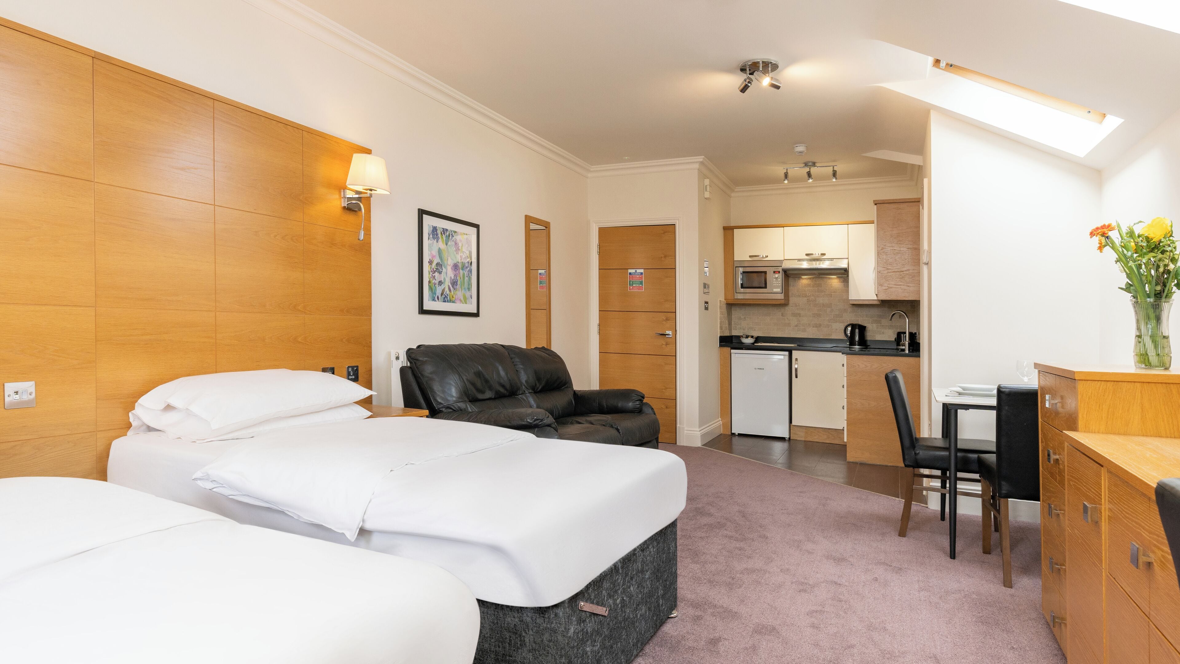 Une chambre d’hôtel avec deux lits, un canapé, une table à manger et un coin cuisine.