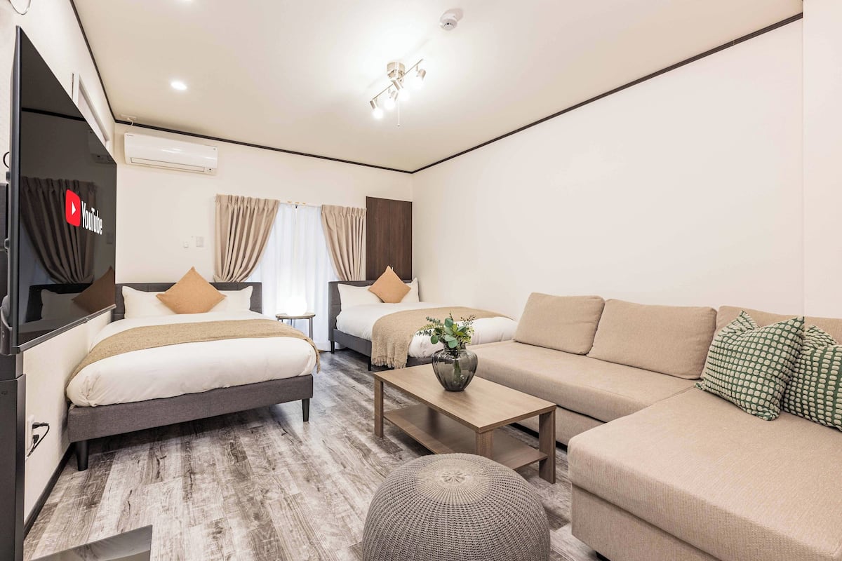 A modern hotel room with a bed, sofa, and TV.