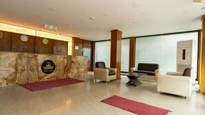 A hotel reception area with a marble reception desk, a clock, and a lounge area with sofas and a coffee table. - Hotel The King's (Port Blair)